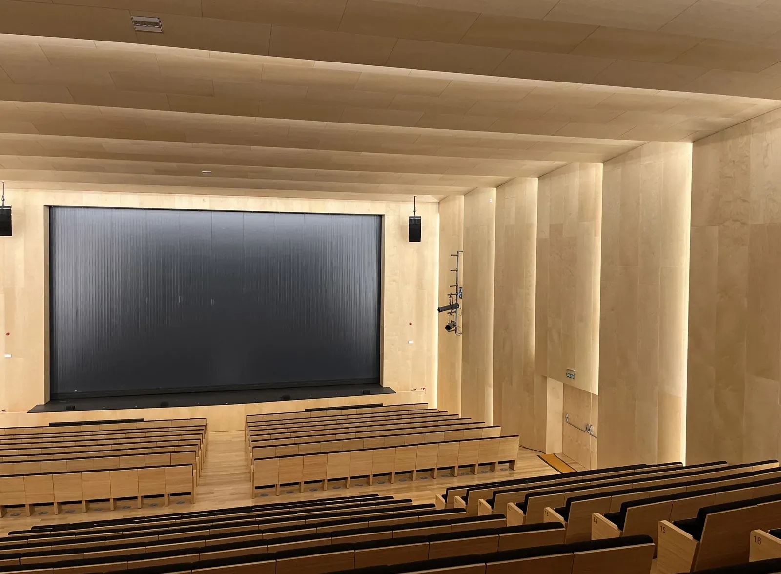 Auditorio con paredes y techo revestidos de paneles acústicos de madera y pantalla de proyección